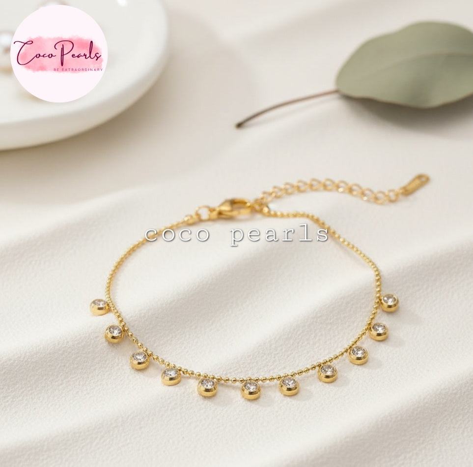Coco Pearls Stainless steel anti tarnish sparkling stars Gold bracelet with small diamonds on a dot ball chain on a beige fabric background