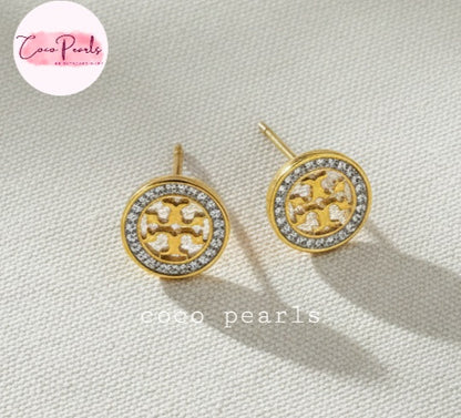 Coco Pearls Stainless Steel Anti Tarnish Gold sparkly vibe earrings with a central design and diamond-like stones on a light fabric background
