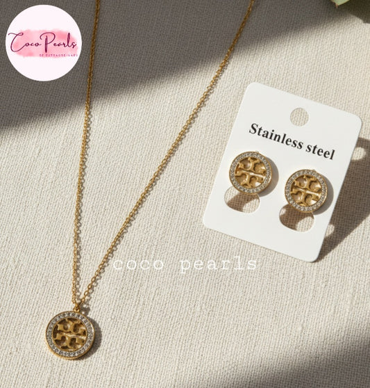 Coco Pearls Stainless Steel Anti Tarnish Gold sparkly vibe set with necklace and  earrings with a central design and diamond-like stones on a light fabric background