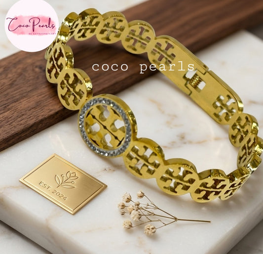 Coco pearls stainless Steel anti tarnish gold sparkly vibe handcuff displyed on simple background 