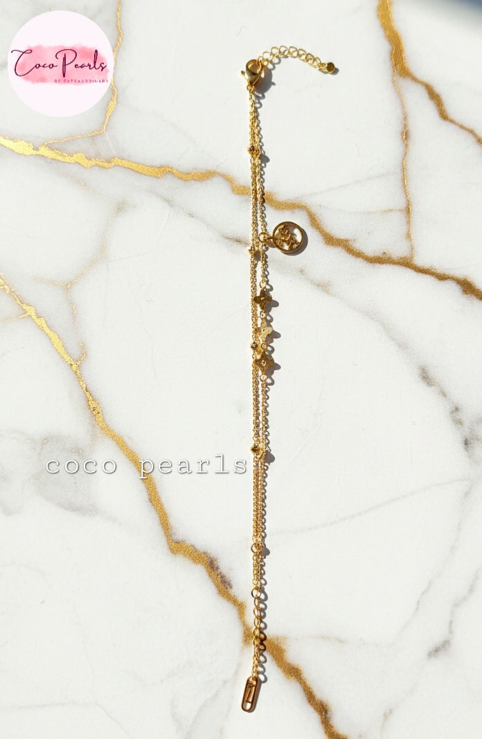 coco Pearls Stainless steel anti tarnish gold starlight bracelet wit dual chain and charm displayed o marble surface