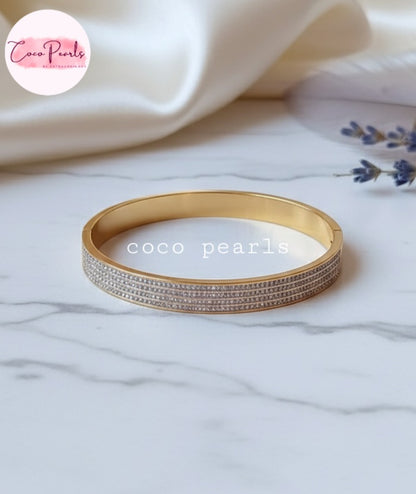 Coco Pearls Stainless Steel Anti tarnish gold stellar stack handcuff bangle bracelet with 4 lines of diamonds displayed on marble surface