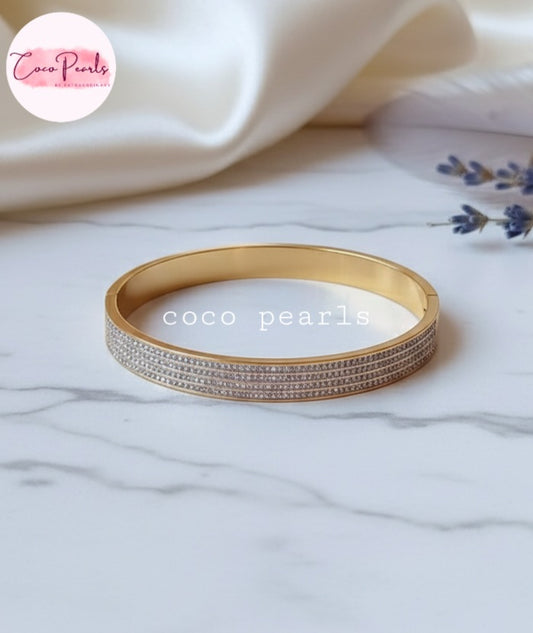 Coco Pearls Stainless Steel Anti tarnish gold stellar stack handcuff bangle bracelet with 4 lines of diamonds displayed on marble surface