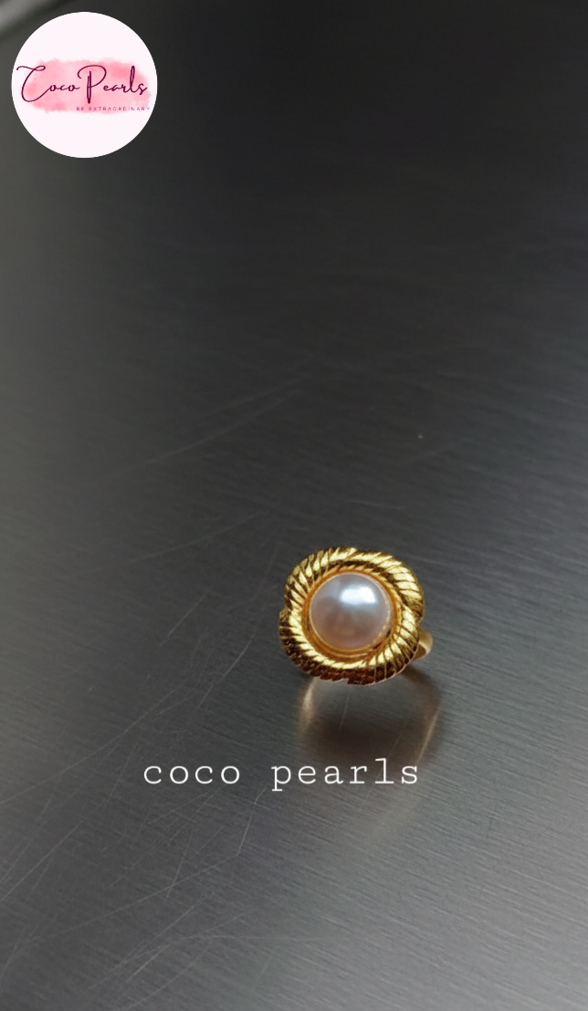 coco pearls stainless steel anti tarnish gold sun kissed pearl adjustable ring  with pearl in center of gold flower displayed on metallic surface