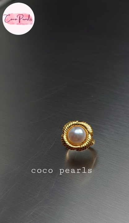 coco pearls stainless steel anti tarnish gold sun kissed pearl adjustable ring  with pearl in center of gold flower displayed on metallic surface