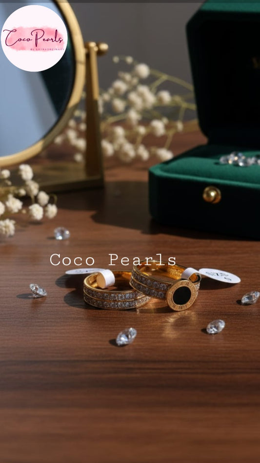 Coco Pearls Stainless Steel Anti Tarnish Gold timeless ring jewelry with black center and diamond studded band on a wooden surface