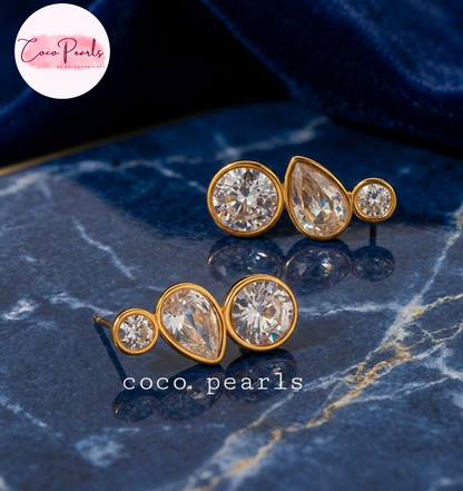 coco pearls stainless steel anti tarnish tri sparkle studs Gold and crystal earrings on a blue surface