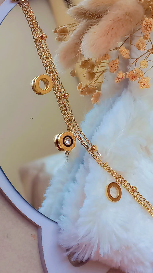 Coco Pearls Stainless steel anti tarnish Gold necklace with circular pendants on a white feathered surface