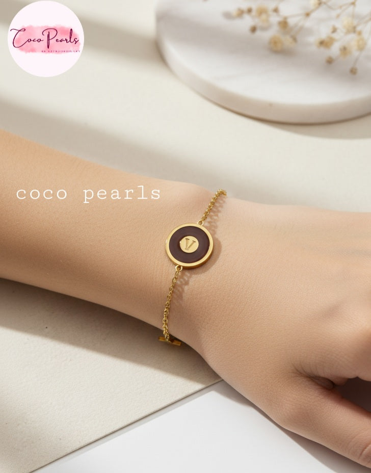 Coco Pearls Stainless Steel Anti tarnish Gold and brown v link bracelet with v initial on brown charm in center and golden charms on either side displayed on hand
