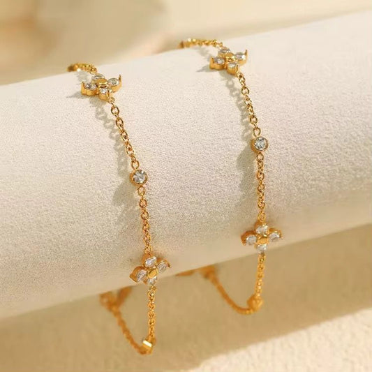 Coco Peals Stainless Steel anti  tarnish Gold winged beauty bracelet with floral and cross designs on a beige surface